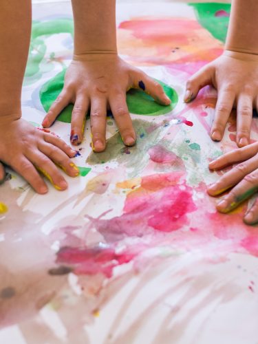 Close up children hands in circle on the table painted with water colors