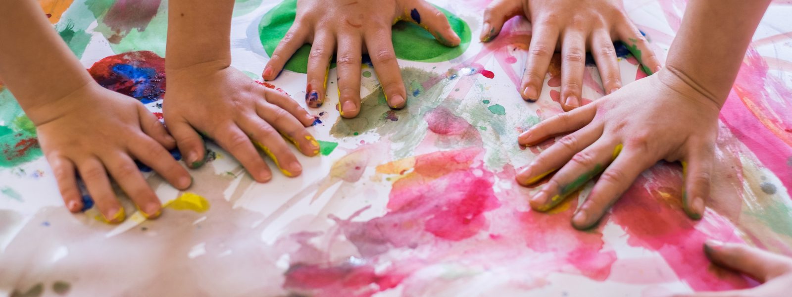 Close up children hands in circle on the table painted with water colors